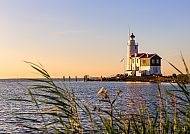 Ijsselmeer, Leuchtturm am Ijsselmeer bei Sonnenuntergang, umgeben von Schilf., Leuchtturm am Ijsselmeer bei Sonnenuntergang, umgeben von Schilf.