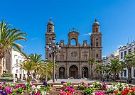 Gran Canaria, Kathedrale von Las Palmas bei strahlend blauem Himmel., Kathedrale von Las Palmas, umgeben von Palmen und Blumen.