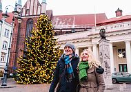 , Paar genießt Weihnachtsstimmung vor geschmücktem Baum in Schwerin., Paar genießt den Weihnachtszauber in Schwerin.