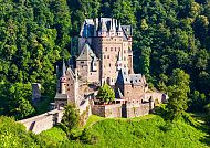 Ausflugstipp: Burg Eltz, Burg Eltz umgeben von üppigem Grün im Sonnenschein.