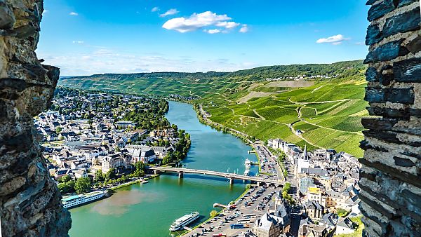 Bernkastel-Kues, Bernkastel-Kues und Mosel im Sommer, umgeben von Weinbergen.