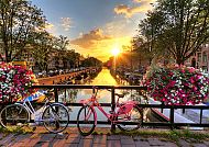 Sonnenuntergang über Amsterdams Kanälen mit Blumen und Fahrrädern.