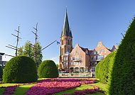Papenburg_St._Antonius_Kirche, St. Antonius Kirche in Papenburg mit gepflegtem Garten im Vordergrund., Papenburg St. Antonius Kirche und Garten in strahlendem Sonnenschein.