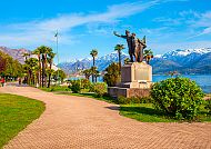 Stresa, Promenade in Stresa mit Statue und Blick auf den Lago Maggiore., Frühlingstag in Stresa am Lago Maggiore mit Bergblick.