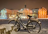 Schloss_Fahrrad im Schnee, Winterliches Schloss Münster mit Fahrrad im Schnee., Verschneites Fahrrad vor beleuchtetem Schloss in Münster.