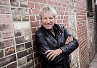 Ihr Stargast an Bord: Bernhard Brink, Bernhard Brink lässig an einer Backsteinmauer.