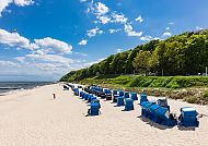 Strandkörbe am Sandstrand von Usedom unter blauem Himmel.