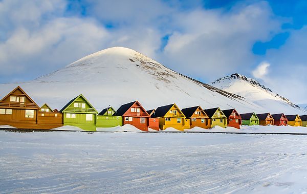 Longyearbyen, Bunte Häuser vor schneebedeckten Bergen in Longyearbyen, Spitzbergen.