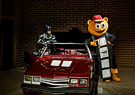 Filmpark Babelsberg, Filmpark Babelsberg: Superheld und Maskottchen posieren am Auto., Filmpark Babelsberg: Comic-Helden posieren mit rotem Auto.