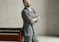 Bart Szopinski, Bart Szopinski vor einer Orgel in elegantem Anzug.