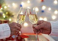 Silvester, Festlicher Silvester-Toast mit Sektgläsern vor Lichterhintergrund.