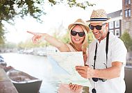 , Paar genießt sonnigen Tag in Amsterdam mit Karte und Lächeln.