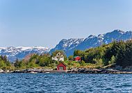 Maloy, Norwegische Fjordlandschaft mit roten Hütten und schneebedeckten Bergen., Idyllische Landschaft mit Fjord und schneebedeckten Bergen.