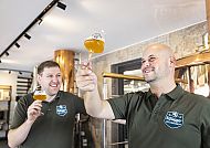 , Bierverkostung mit Freude und Expertise in gemütlicher Brauereiatmosphäre., Zwei Männer genießen Bier bei einer Führung, lächelnd und zufrieden.