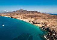 Küste von Lanzarote mit türkisfarbenem Meer und Segelboot.