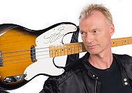 Sting, Sting mit signiertem Bass auf der OLDIE ANTENNE Partyboot 2.0., Mann mit signierter Gitarre auf der Schulter, lächelnd.