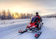 Auf Nordlichtsuche in Finnland, Schneemobil-Abenteuer bei Sonnenuntergang in Lappland, Finnland.