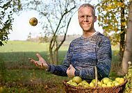 Gartenberater Philippe Dahlmann, Philippe Dahlmann im Obstgarten mit Korb voller Äpfel., Philippe Dahlmann im herbstlichen Garten mit Apfelkorb.