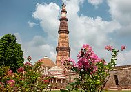 Qutb Minar, Delhi, Qutb Minar in Delhi, umgeben von blühenden Blumen und blauem Himmel., Qutb Minar in Delhi, umgeben von blühenden Blumen und blauem Himmel.