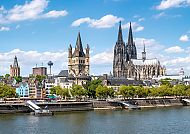 Kölner Dom und Altstadt am Rhein unter blauem Himmel.