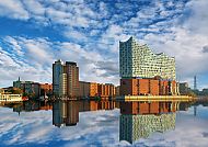 Hamburg, Hamburgs Elbphilharmonie spiegelt sich im Wasser unter blauem Himmel., Elbphilharmonie spiegelt sich im Wasser, Hamburgs Skyline im Sonnenschein.