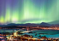 Nordlichter über Tromsø mit malerischer Brücke und Stadtansicht.
