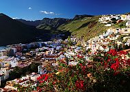 , Bunte Häuser in San Sebastian vor grünen Bergen und blauem Himmel., Bunte Hügellandschaft in San Sebastian, Spanien.