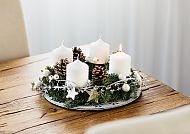 Adventskranz mit Kerzen und Tannenzapfen auf Holztisch.