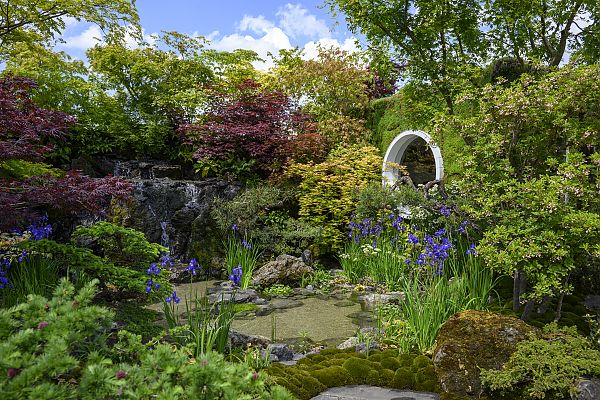 , Üppiger Garten mit Wasserfall und bunten Blumen bei der Chelsea Flower Show.