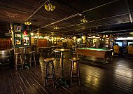 Gemütliche Bar mit Holzmöbeln und Billardtisch in warmem Licht.