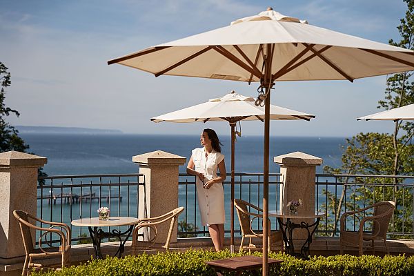 aja Nordperd & Villen, Frau auf Terrasse mit Meerblick im aja Nordperd & Villen Göhren.