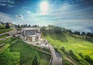 Hotel Brenta Dolomites umgeben von grünen Hügeln und strahlendem Himmel.
