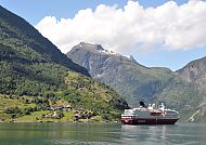 Kreuzfahrtschiff im Fjord vor beeindruckender Berglandschaft.