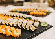 Verschiedene Sushi-Rollen auf schwarzem Tablett, appetitlich angerichtet.
