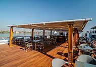 Sonnige Terrasse mit Holzmöbeln und Flussblick.