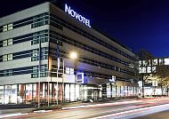 Moderne Hotelansicht bei Nacht mit beleuchtetem Novotel-Logo.