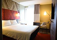 Modernes Hotelzimmer mit Doppelbett und Schreibtisch, gemütliche Atmosphäre.
