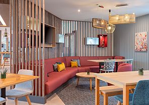 Moderne Lounge mit roten Sofas, Holzmöbeln und gemütlicher Atmosphäre.