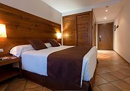 Gemütliches Hotelzimmer mit Doppelbett und Holzmöbeln.