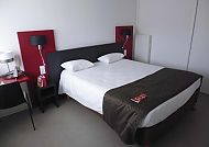 Modernes Hotelzimmer mit stilvollem Doppelbett und roten Akzenten