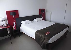 Modernes Hotelzimmer mit stilvollem Doppelbett und roten Akzenten