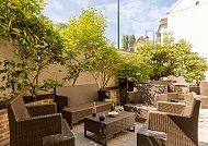 Gemütliche Terrasse im Hotel Le Cardinal, umgeben von Grün