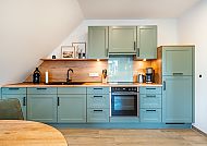 , Moderne Küche in sanften Grüntönen im Apartment in Greetsiel., Moderne Küche Feerjenkoje im Hotel 'Apartmentauswahl in Greetsiel'.