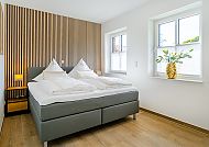 , Modernes Schlafzimmer mit stilvollem Holzdesign und gemütlichem Bett.