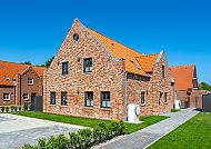 , Apartmentauswahl in Greetsiel, charmante Backsteinarchitektur., Apartmentauswahl in Greetsiel mit rotem Backstein und blauen Himmel.