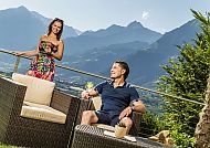 Paar auf der Terrasse mit Aperitif, Paar genießt Aperitif auf Terrasse mit Bergblick im Astor Hotel Schenna.