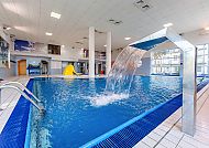 Modernes Hallenbad mit Wasserfall und heller Atmosphäre