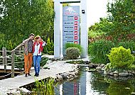 Paar spaziert im Grünen am Hotel Ikar Plaza entlang eines Teichs