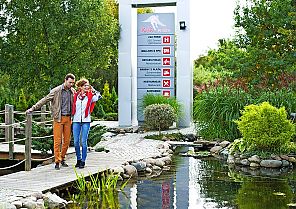 Paar spaziert im Grünen am Hotel Ikar Plaza entlang eines Teichs
