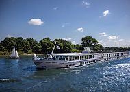 , Kreuzfahrtschiff 'Thurgau Saxonia' auf einem idyllischen Fluss., Flusskreuzfahrtschiff 'Thurgau Saxonia' auf sonniger Wasserstraße.